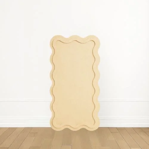 Empty decorative frame with a wavy border standing against a white wall.