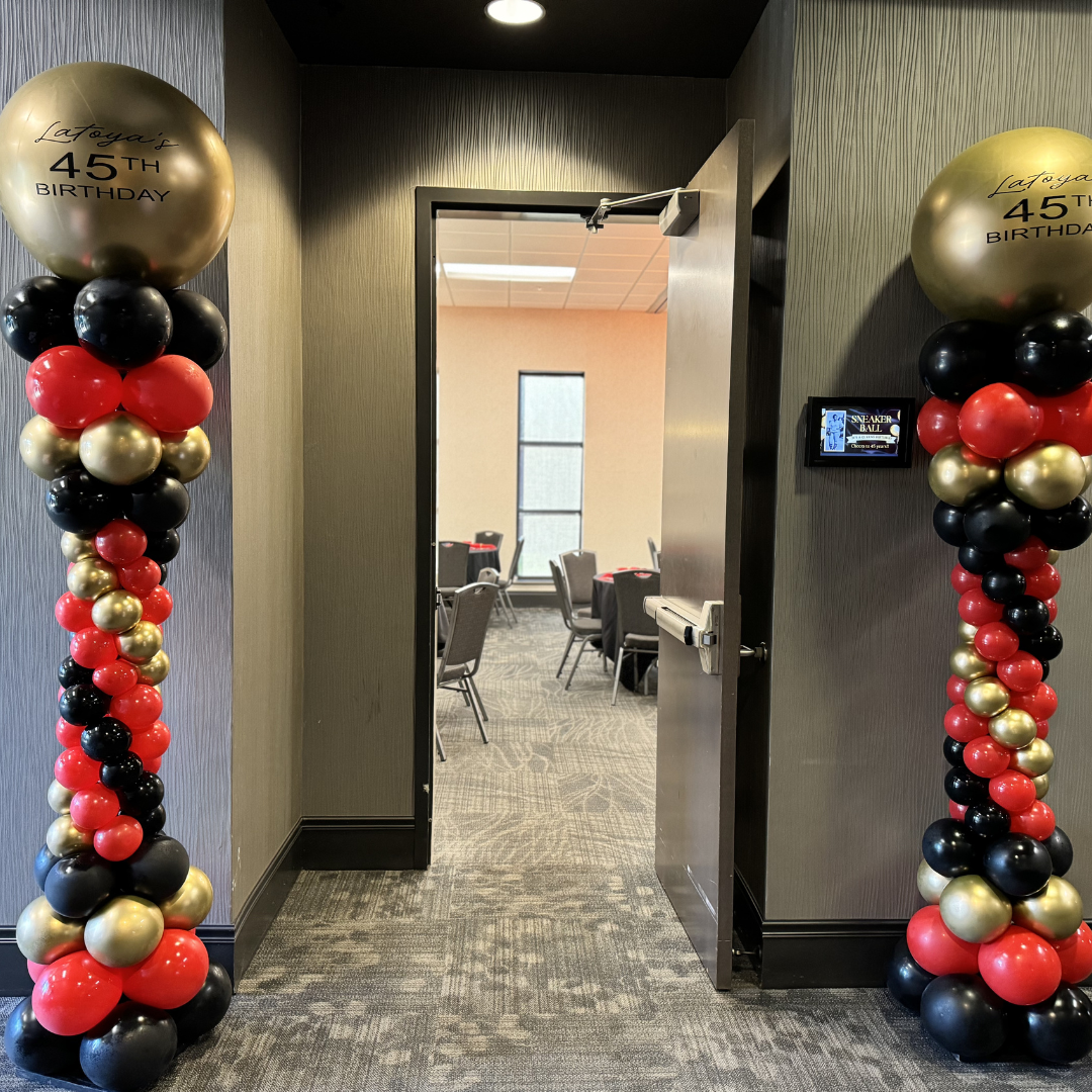 Decorative balloon columns with gold, black, and red balloons leading to a room for Latoya's 45th birthday celebration.