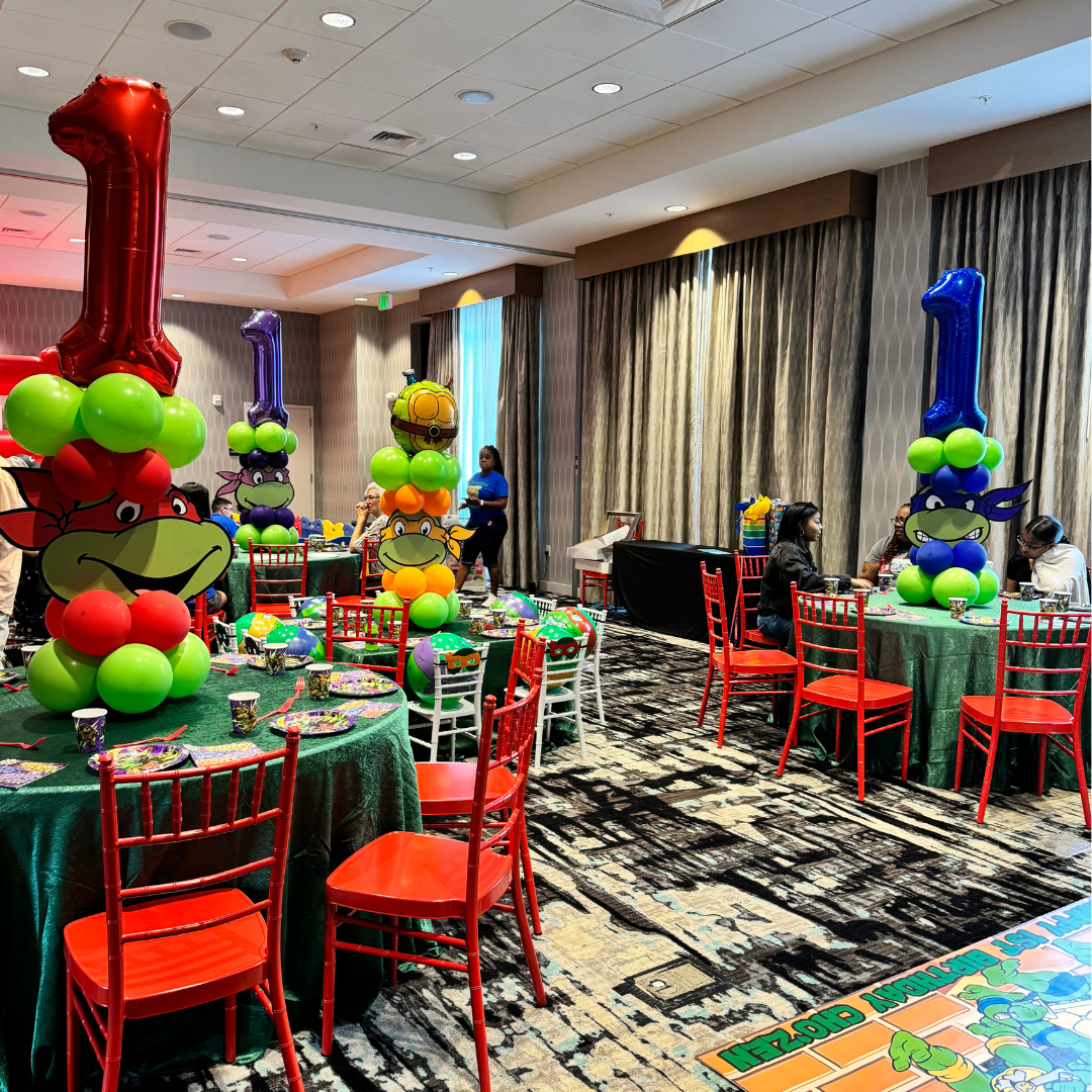 Children's birthday party decorations featuring Teenage Mutant Ninja Turtles theme with balloons shaped like turtles, and tables set for a celebration.