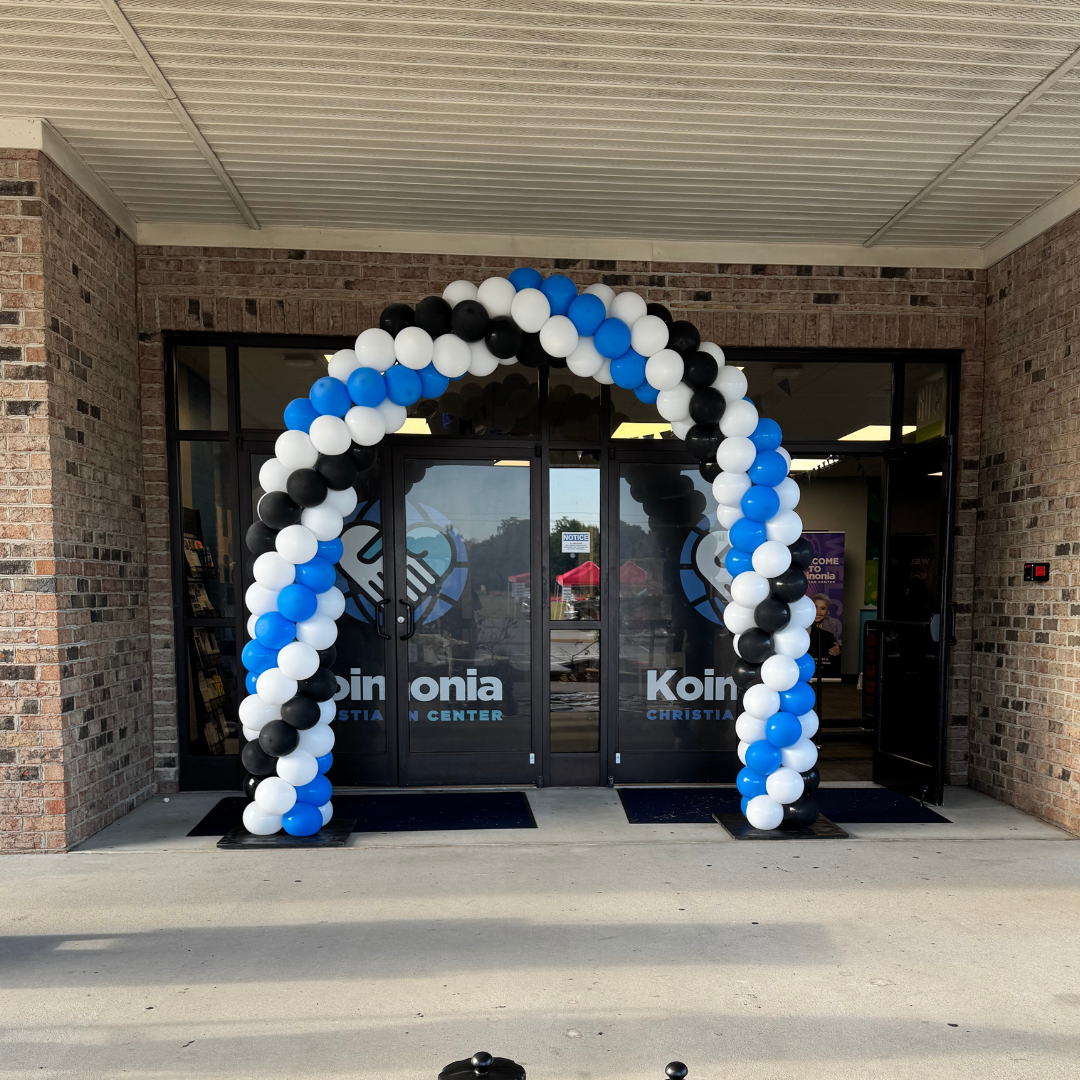 Entrance to a Christian center with a balloon arch door decoration in black, white, and blue balloons.