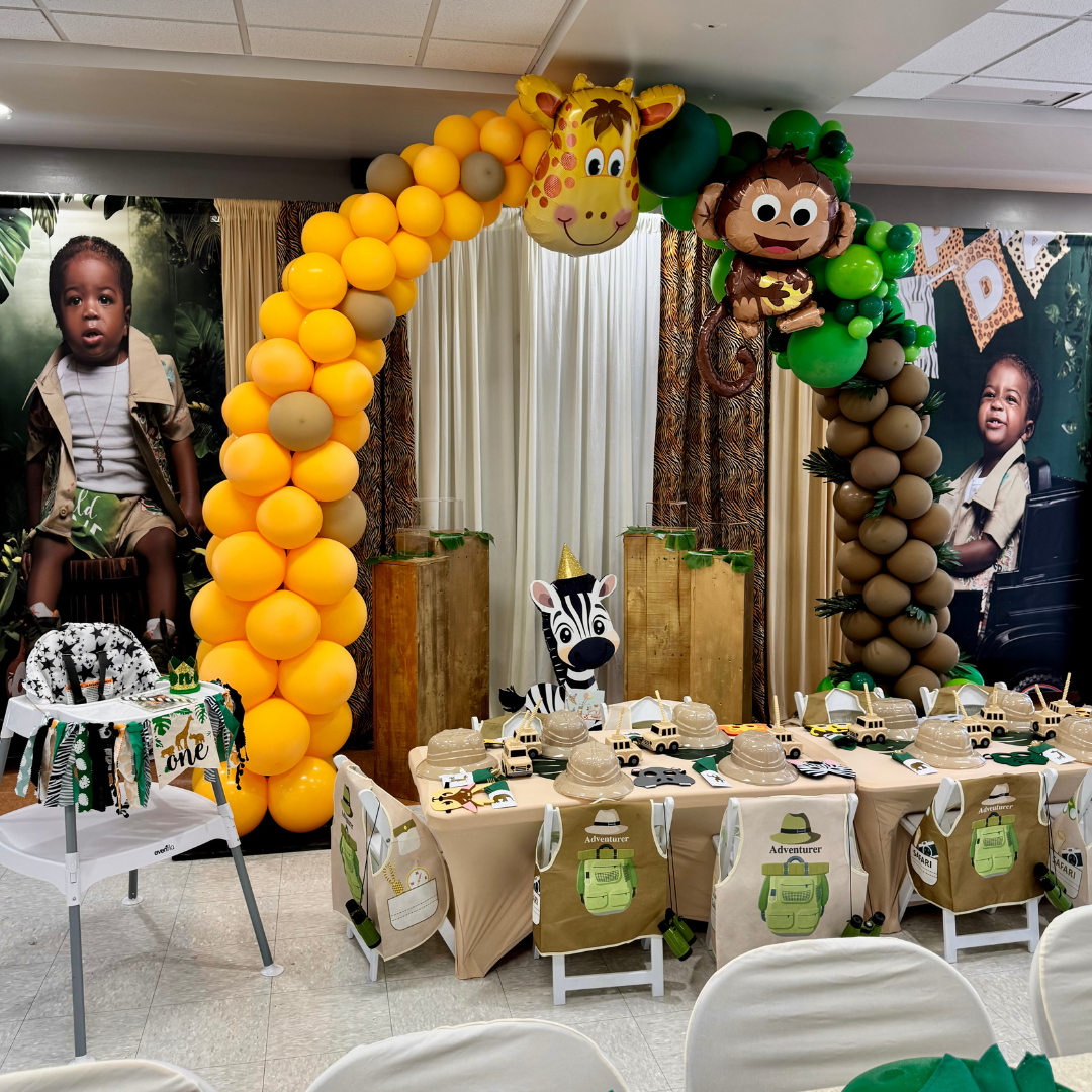 Zoo safari-themed birthday party setup with animal balloons, posters of children, a decorated table with safari-themed items, and chairs for guests.