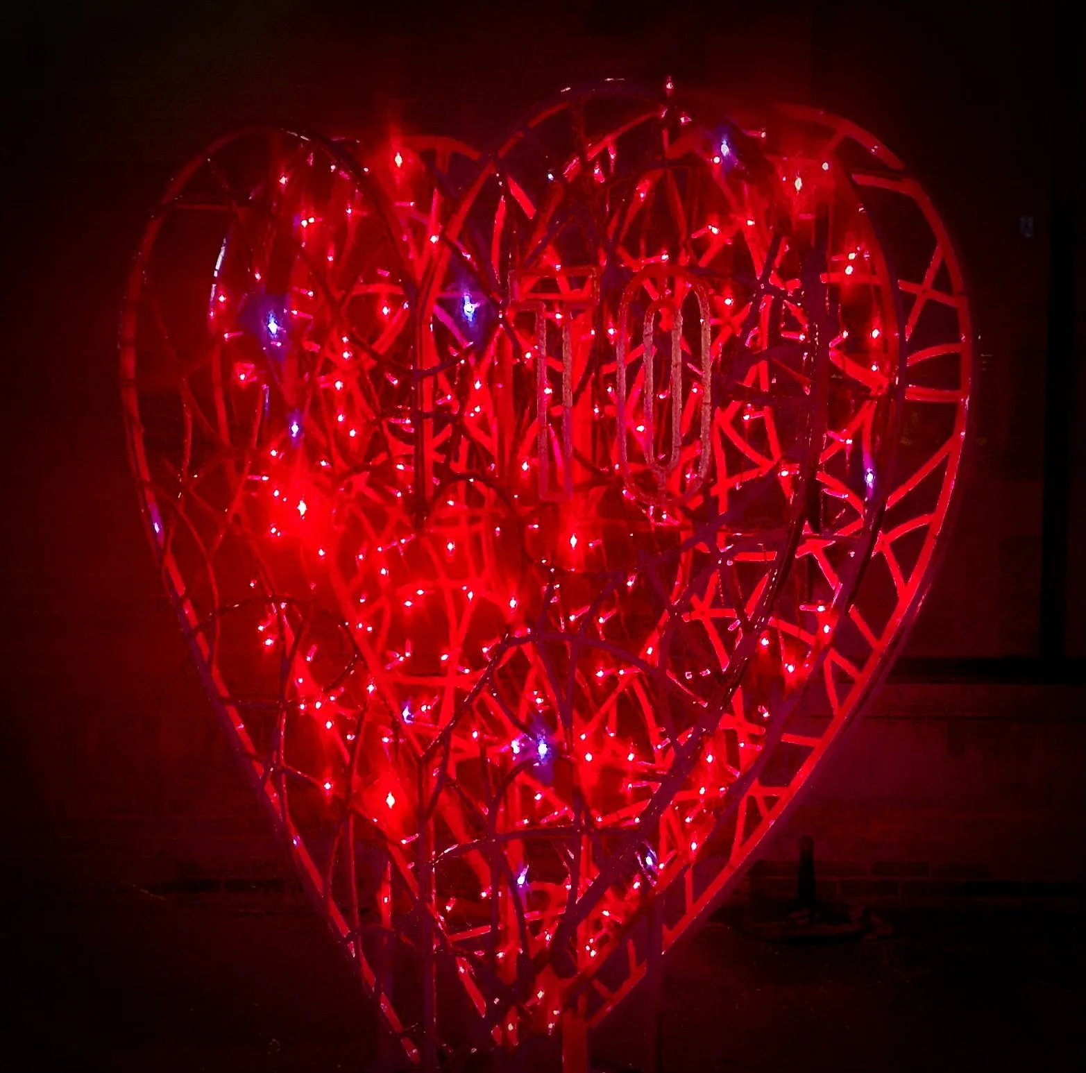 Red heart-shaped sculpture illuminated with lights at night.