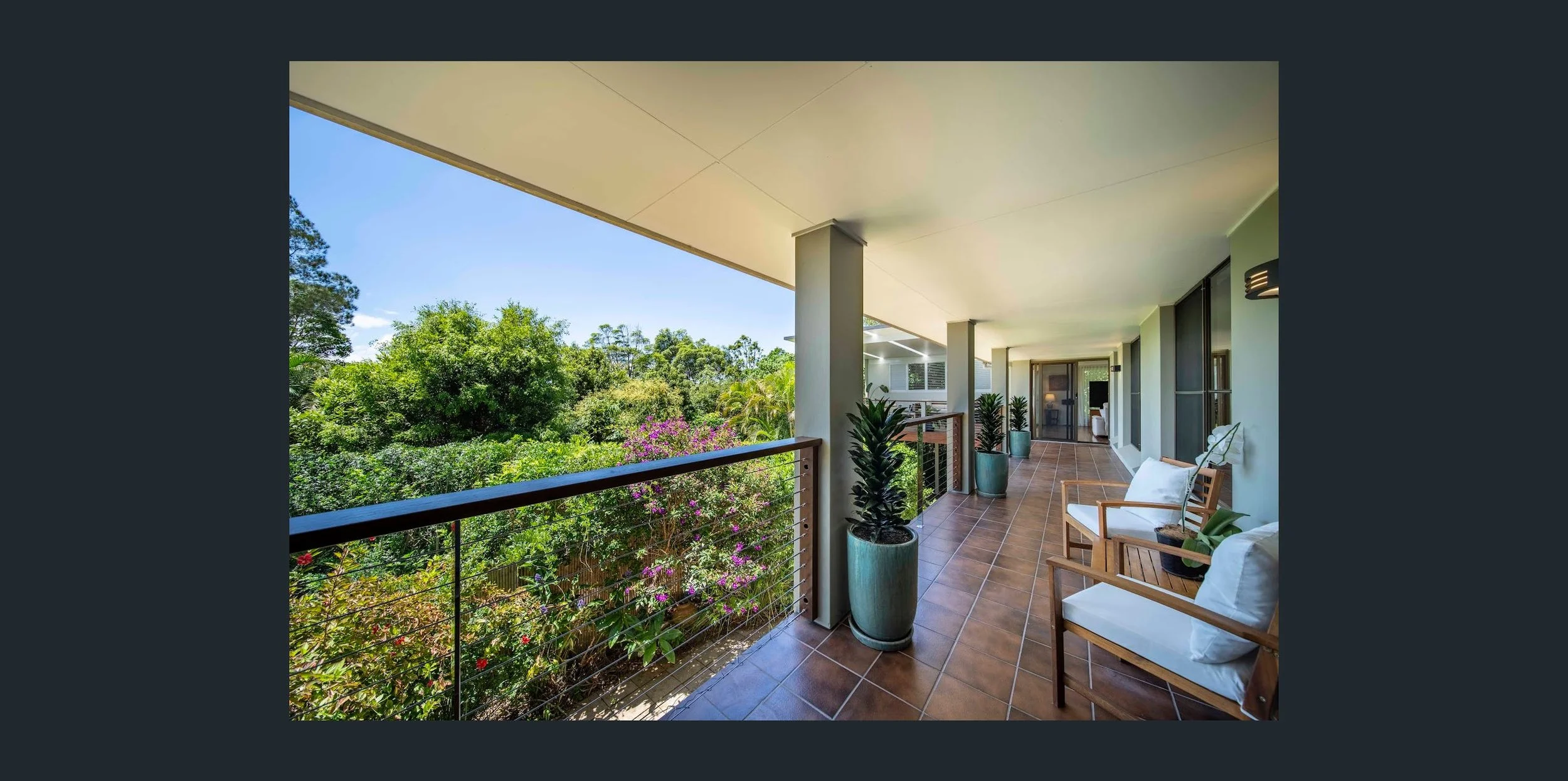 Balcony with potted plants and outdoor seating overlooking lush greenery.