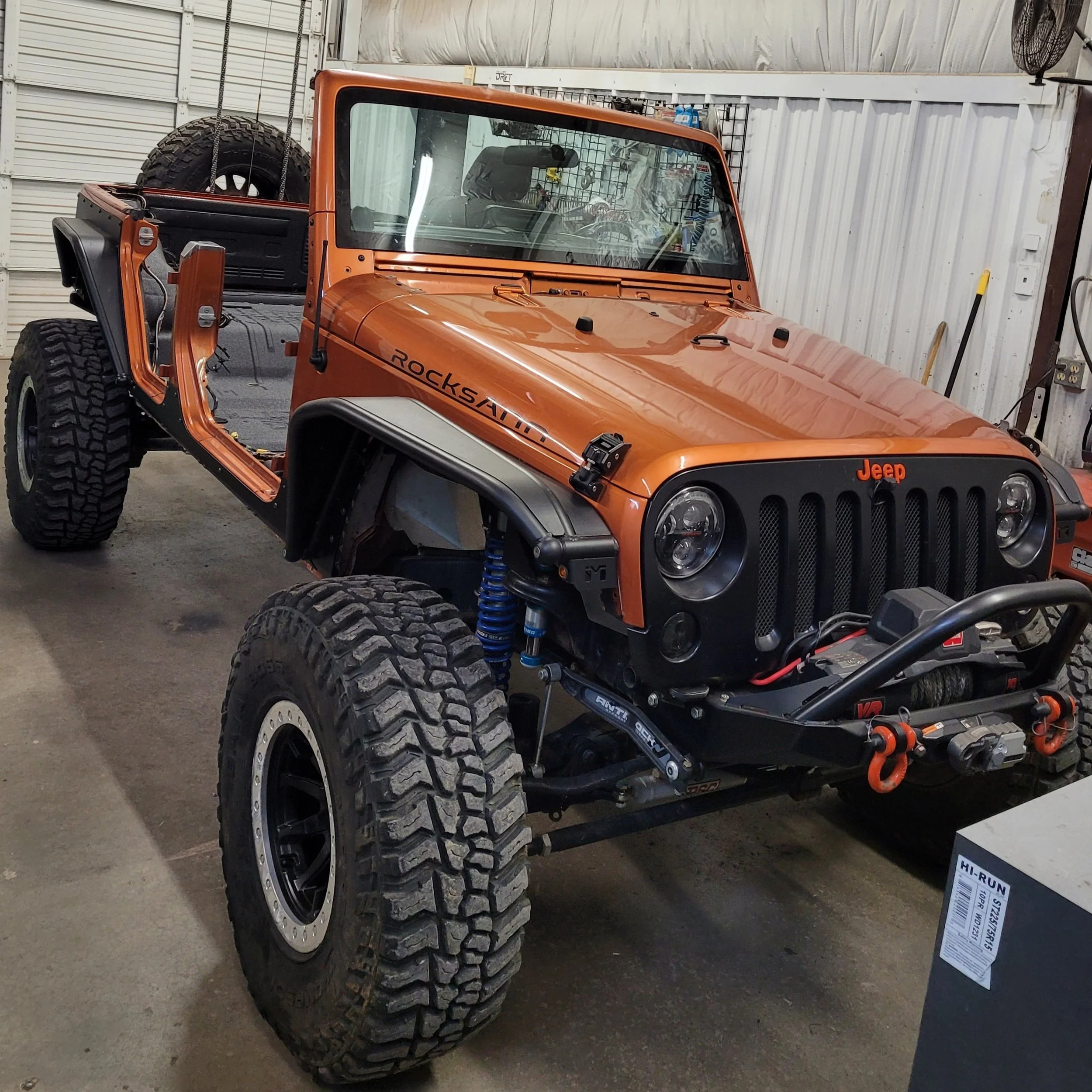 Convertible style orange Jeep in a garage