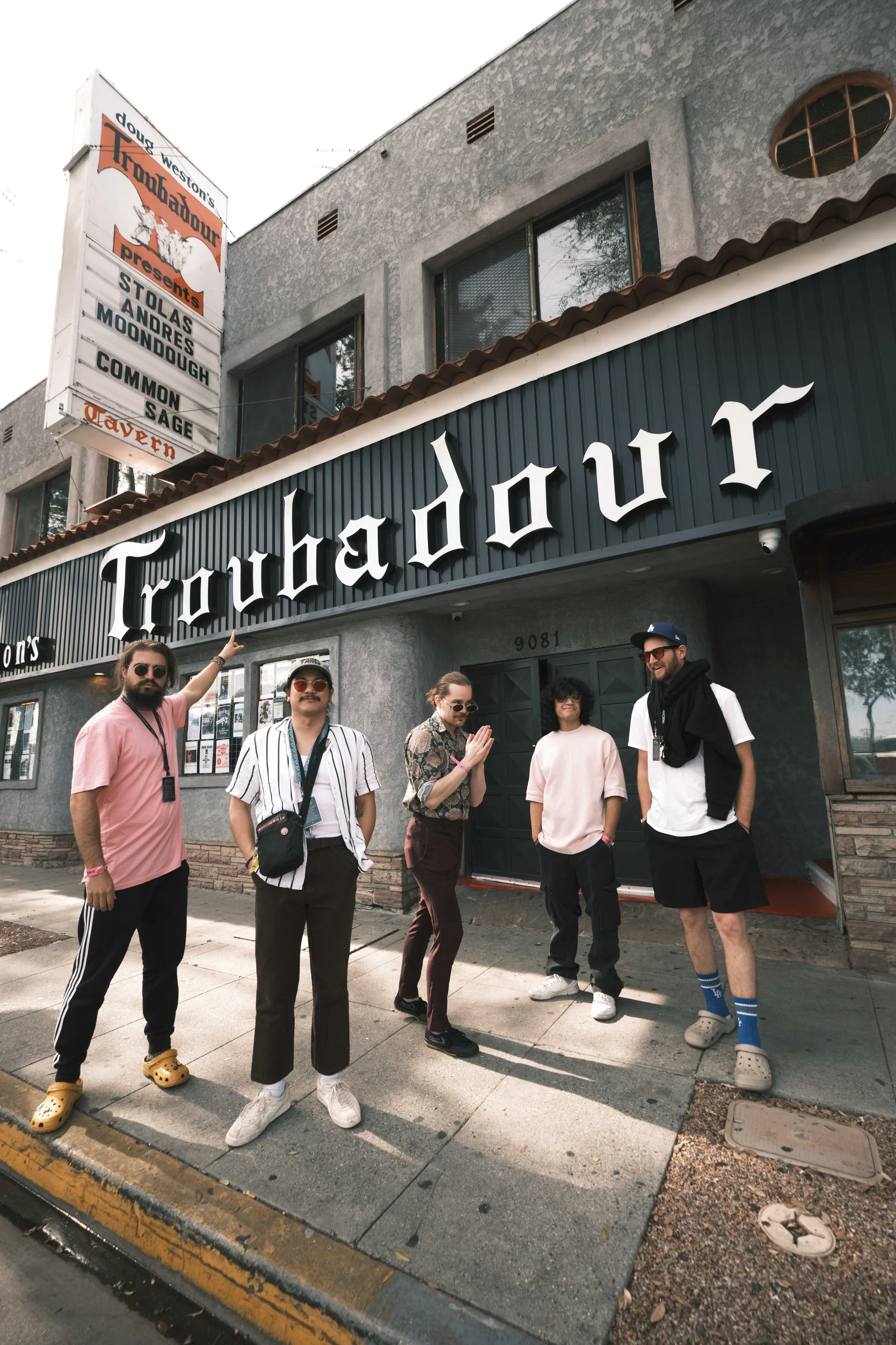Five people standing outside Troubadour music venue, casually dressed, posing and smiling.