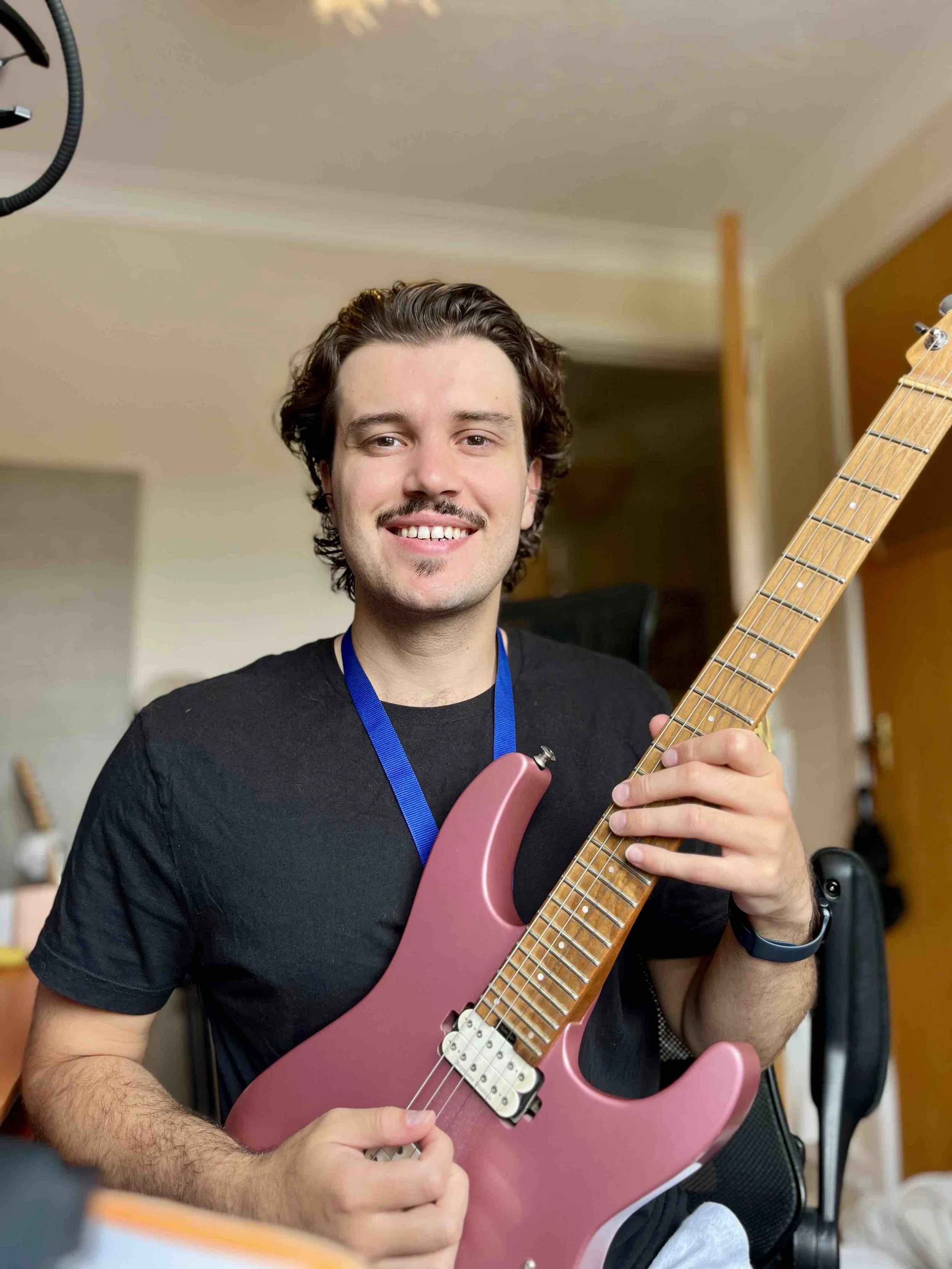 patient and friendly guitar teacher holding an electric guitar and smiling ready to start the lesson