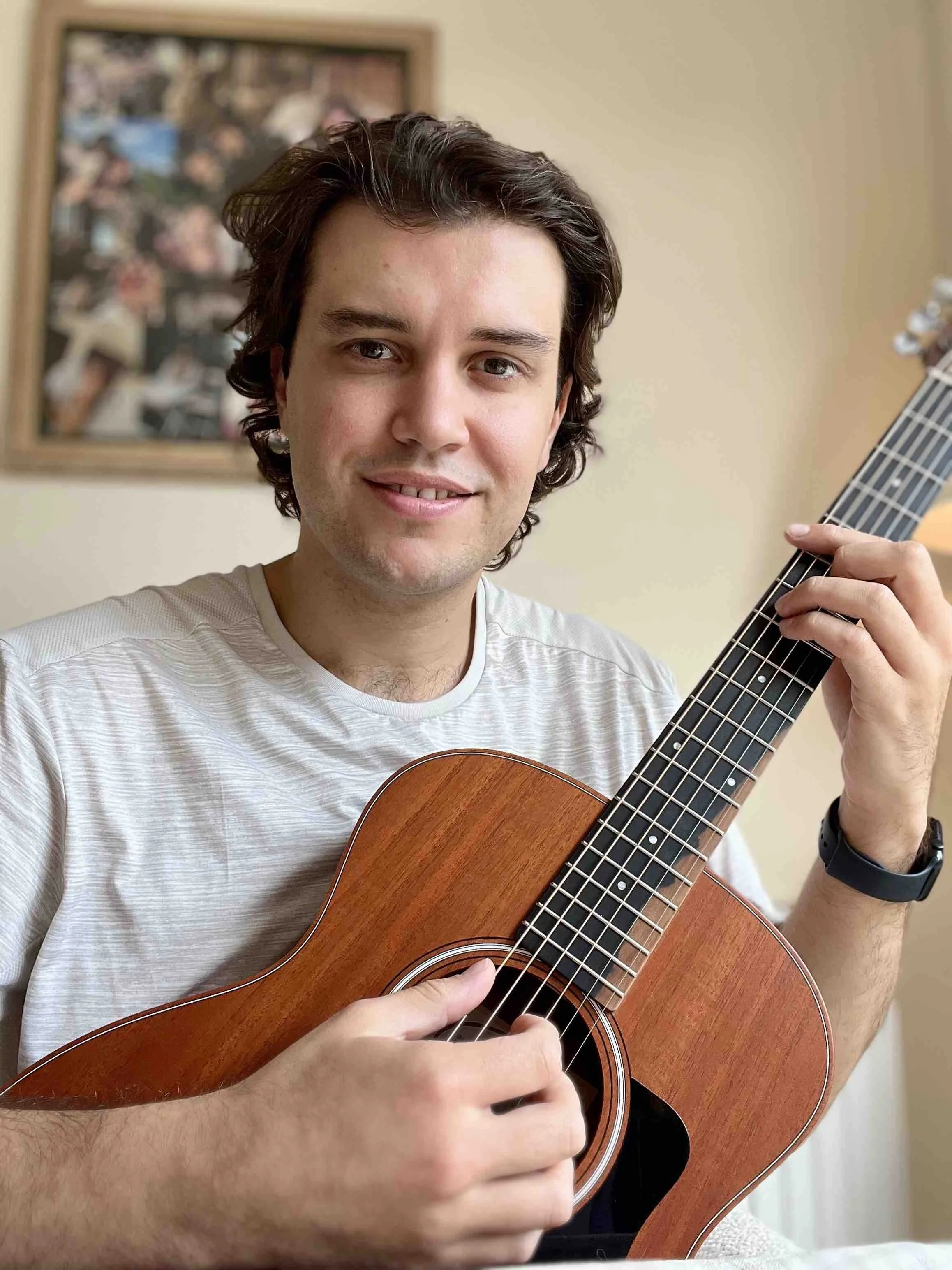 Friendly guitar teaching holding acoustic guitar smiling and playing bar chord