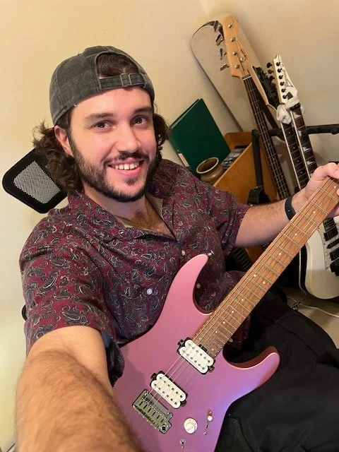 friendly guitar teacher smiles holding his guitar as the online guitar lesson starts.