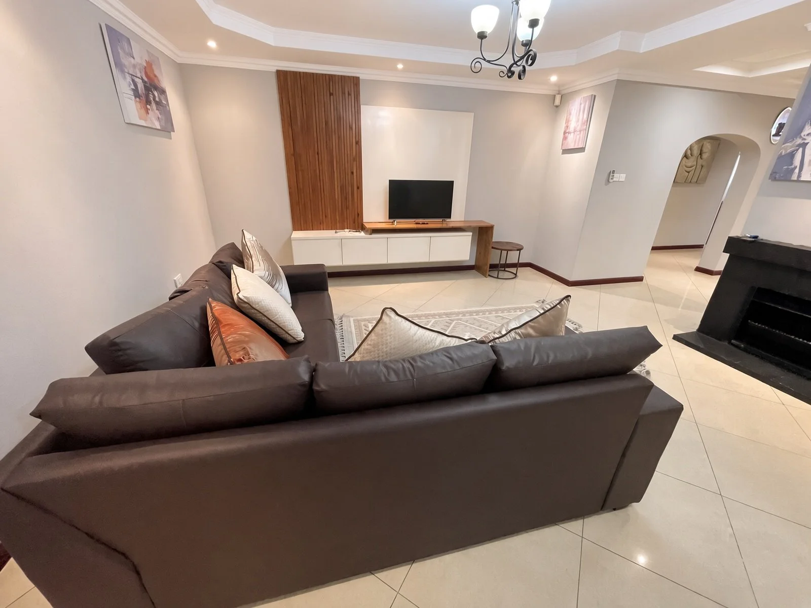 Air-conditioned lounge looking toward the TV unit and fireplace in the spacious 5-bedroom furnished home, Phakalane. Nestgeeks.