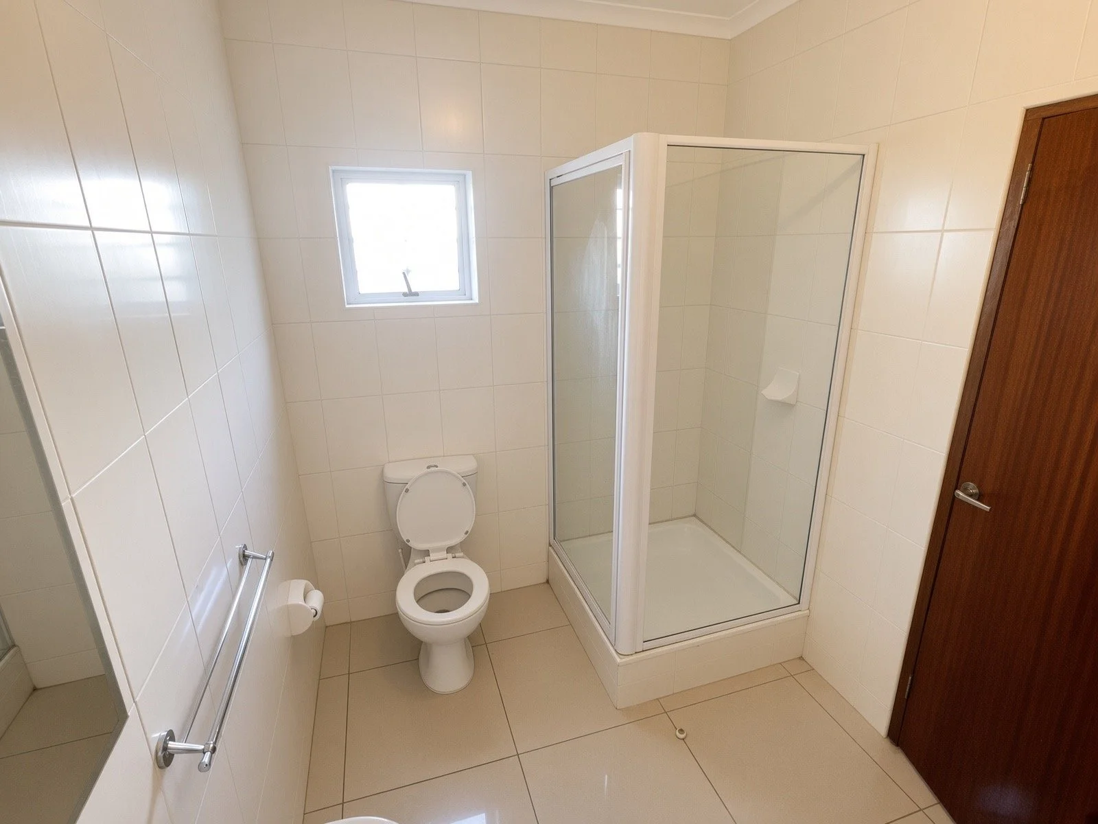 Tiled bathroom with glass shower cubicle and toilet in the 4-bedroom house for rent, gated estate Phakalane. Nestgeeks.