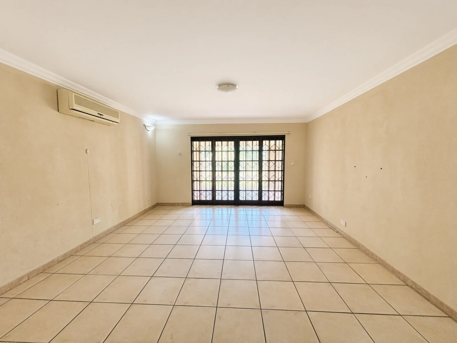 Spacious tiled room with security gates and aircon in a 5-bedroom house for sale in Phakalane Golf Estate