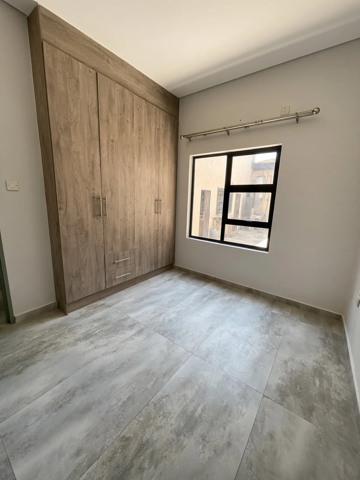 Bedroom with large built-in wardrobe and black-framed window in a 2-bedroom house for rent in Maruapula