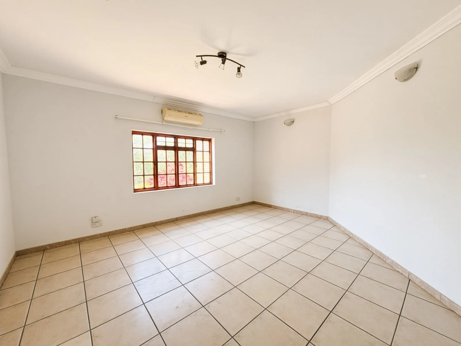 Bedroom with wall-mounted aircon and wooden window in a 5-bedroom Phakalane house for sale