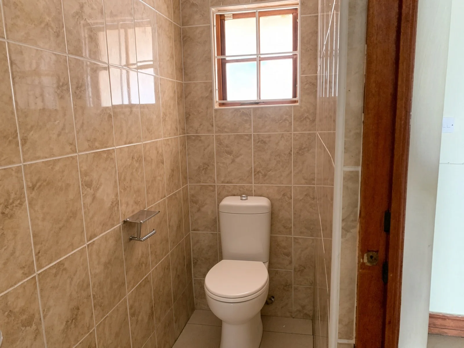 Guest toilet with tiled walls and window in a Phakalane house for rent