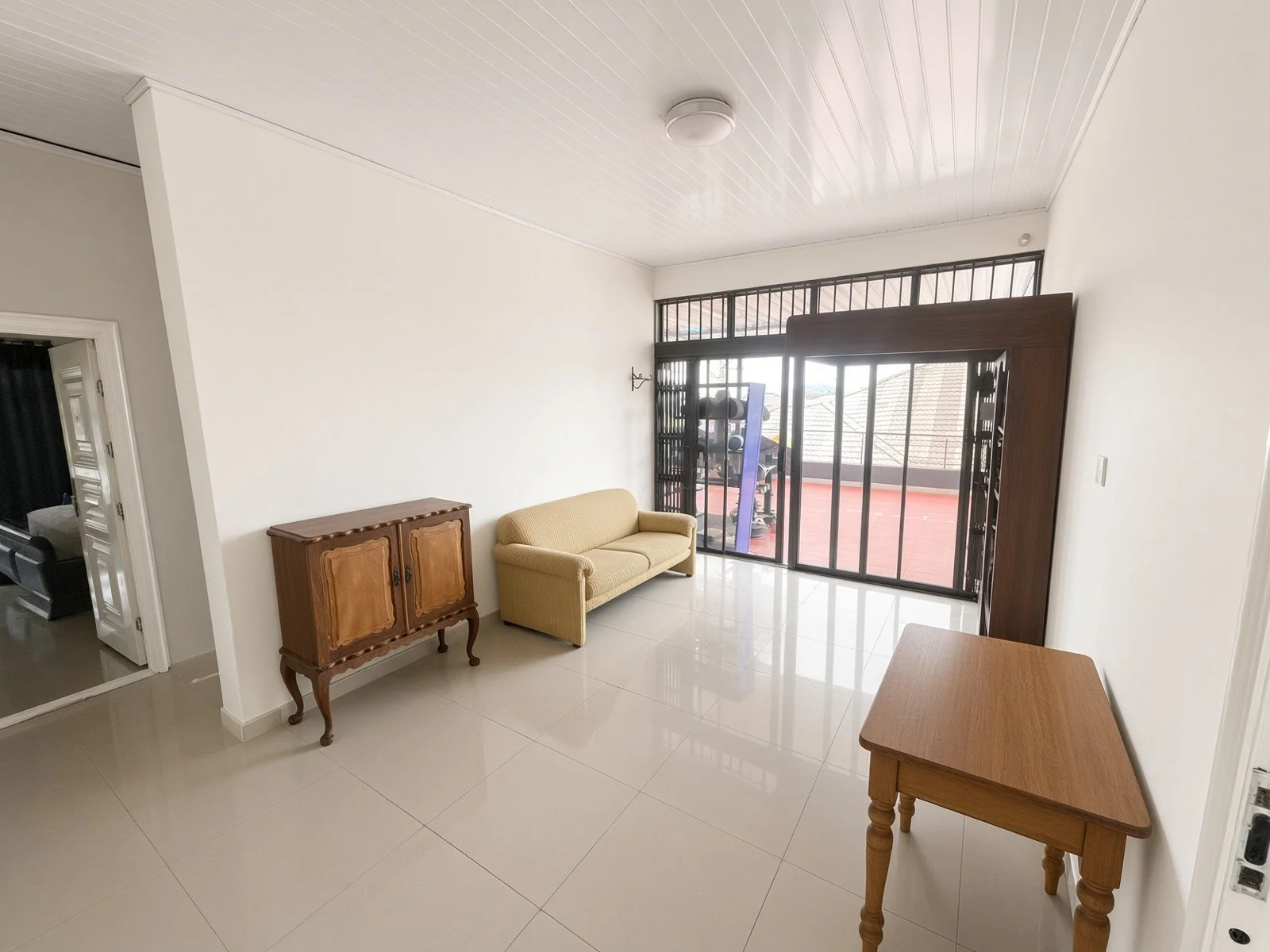 Bright lounge with cream sofa and barred glass doors to the rooftop terrace, house for sale Gaborone