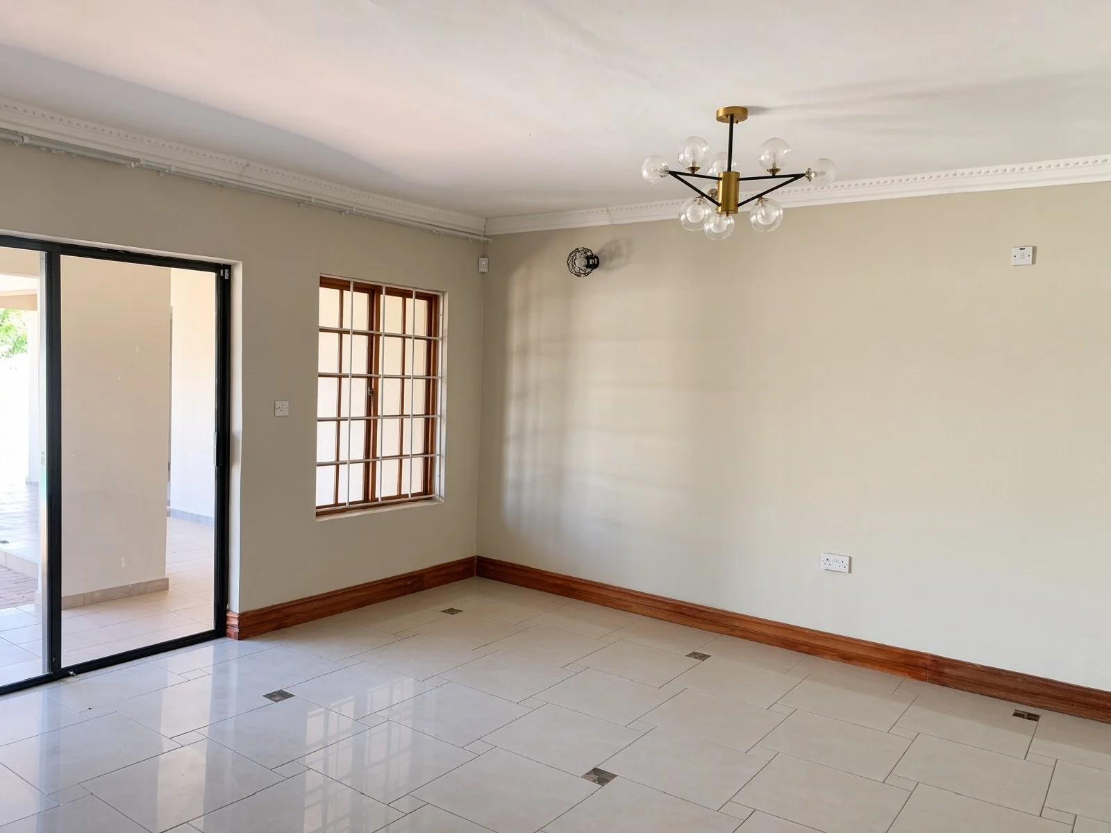 Bright tiled lounge with air conditioning and barred window in a family house for rent in Phakalane