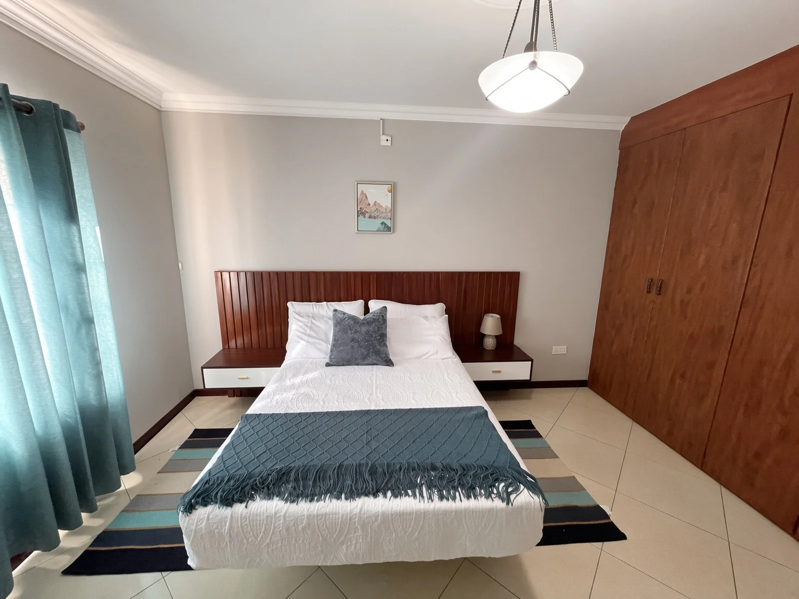 Furnished bedroom with wooden fitted wardrobe, slat headboard and air conditioning in the 5-bedroom Phakalane rental home. Nestgeeks property.