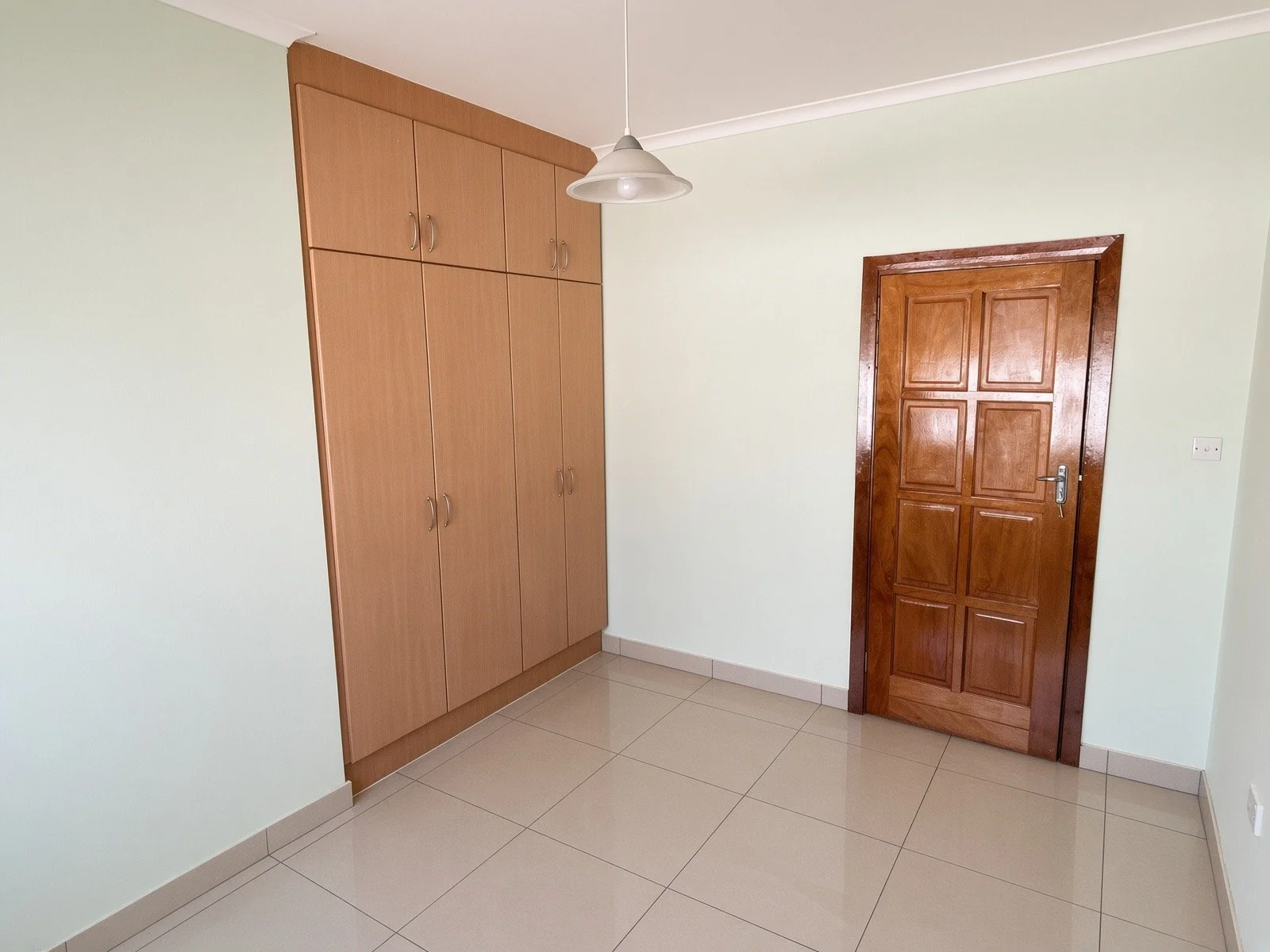 Bedroom with built-in wooden wardrobes and solid wood door in the 4-bedroom house for rent, Phakalane. Nestgeeks property.