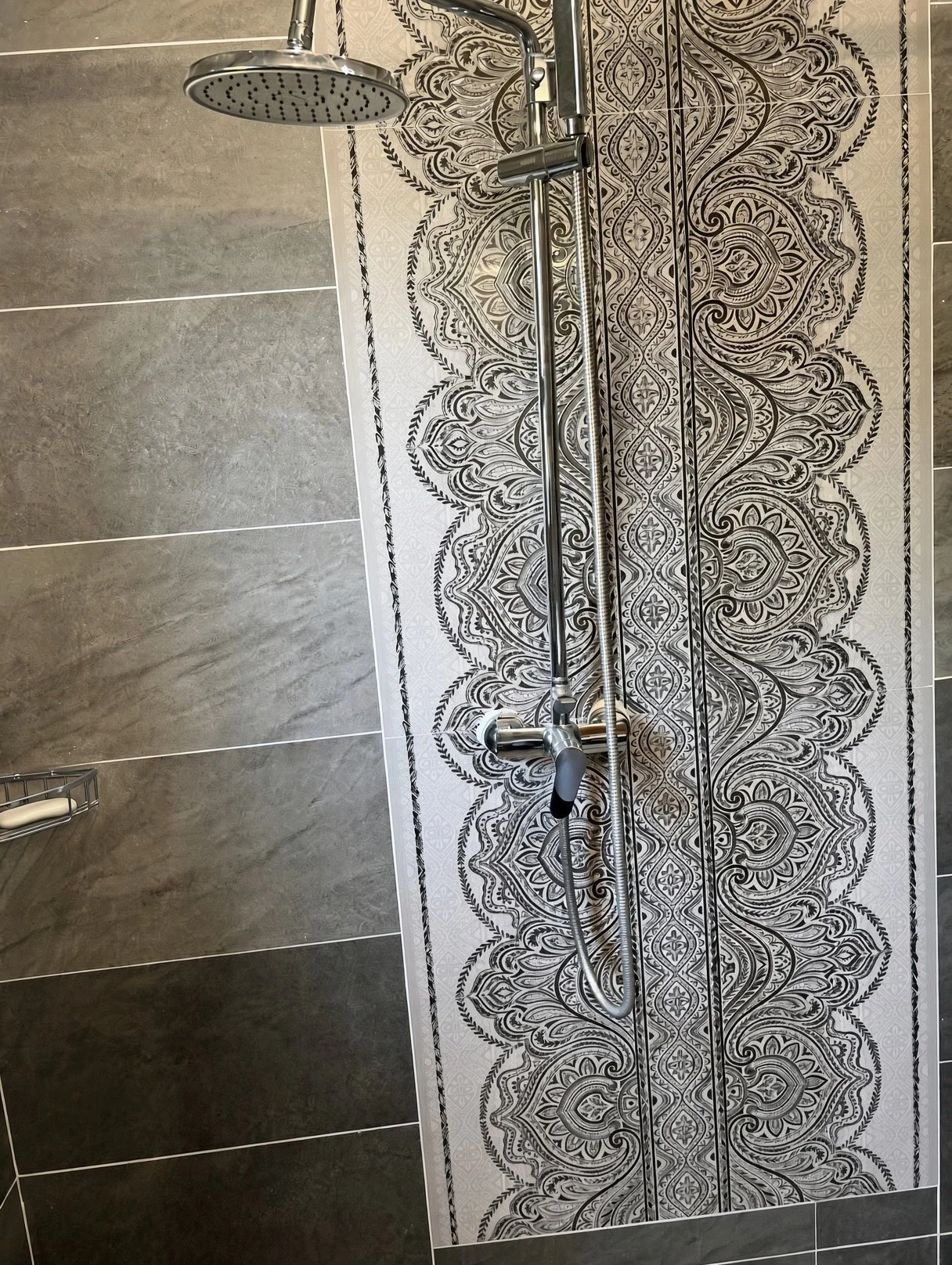 Chrome rain shower and handheld mixer on decorative tiled wall in a Gaborone apartment for rent