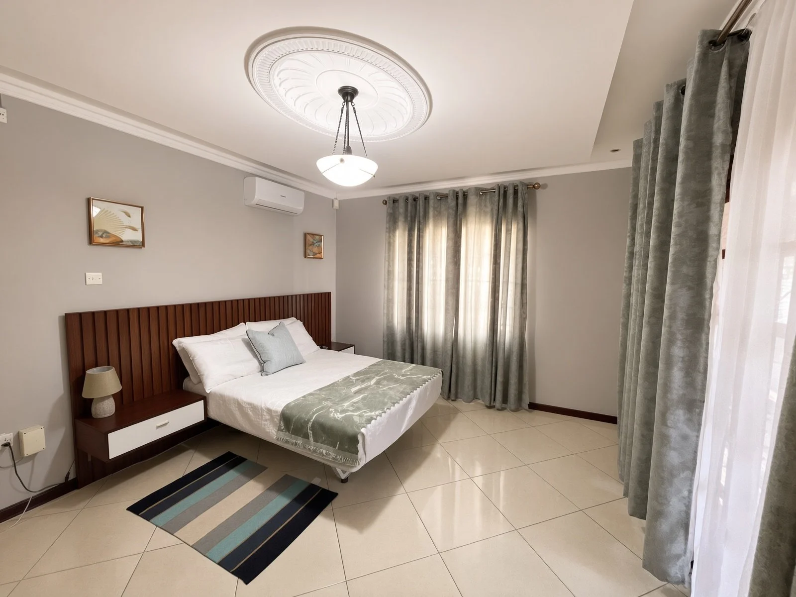 Bright air-conditioned bedroom with slat headboard and full-length curtains in the fully furnished 5-bedroom home, Phakalane. Nestgeeks.