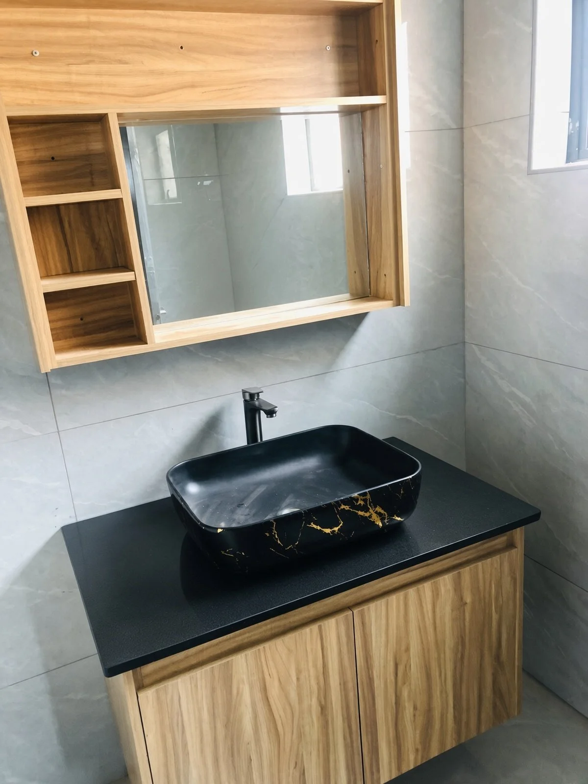 Modern bathroom vanity with black marble-effect vessel basin, gold veining, matte black tap and light-wood cabinets in a 3-bedroom unit for rent in a gated estate, Gaborone North. Nestgeeks listing.