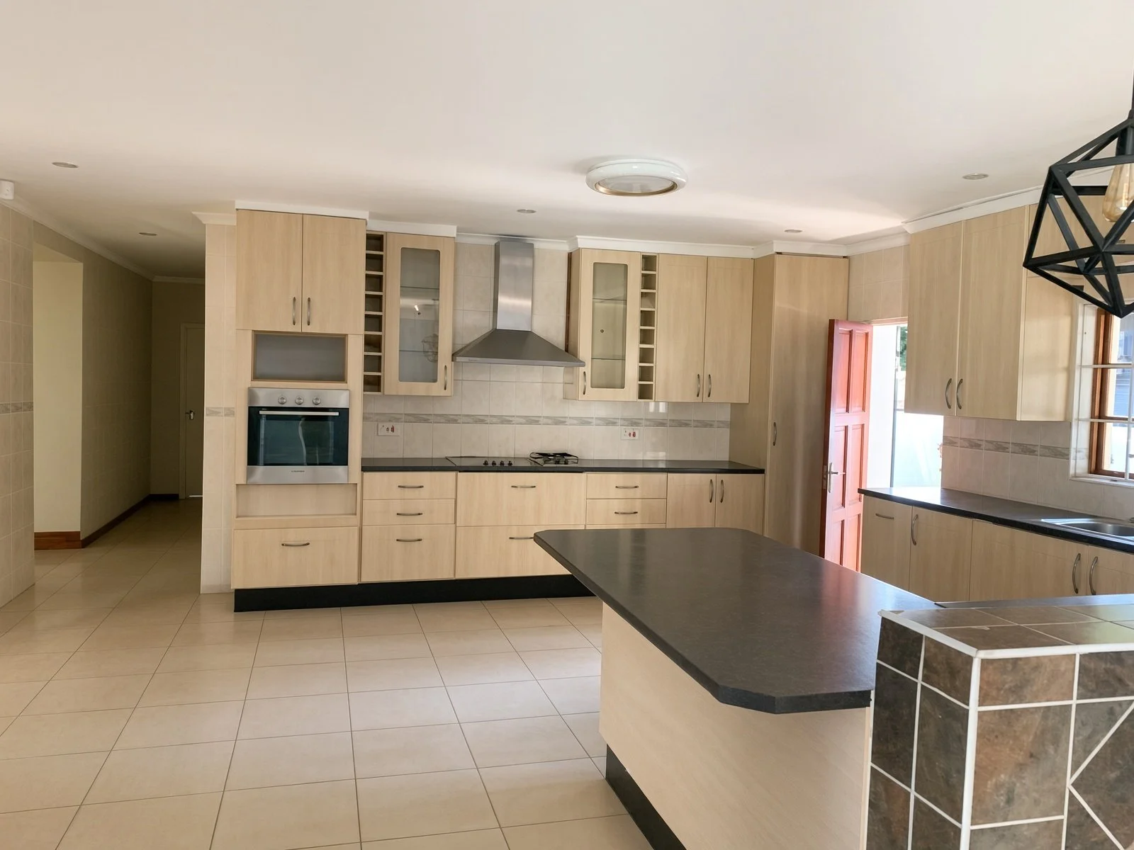 Open kitchen with island opening into a blue lounge with fireplace in a Phakalane house for rent
