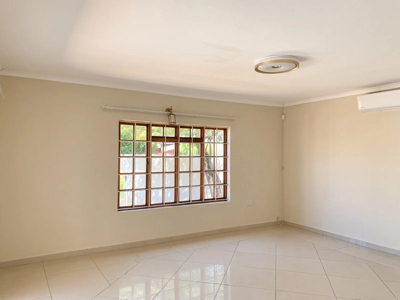 Bedroom with large barred window and air conditioning in a family house for rent in Phakalane