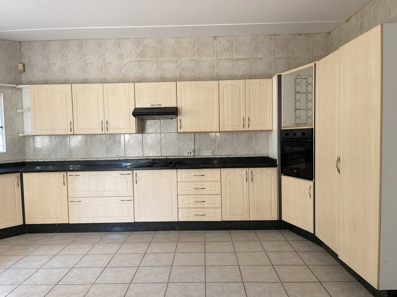 Fitted light-wood kitchen with black counters, extractor and built-in oven in a 5-bedroom house for rent in Block 9 Gaborone