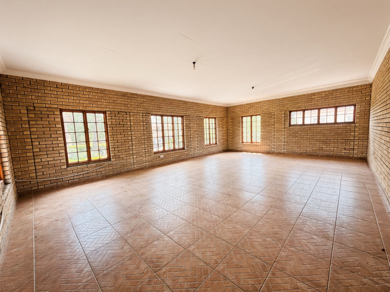 Large room with brick walls and herringbone floor tiles in a Phakalane house for sale
