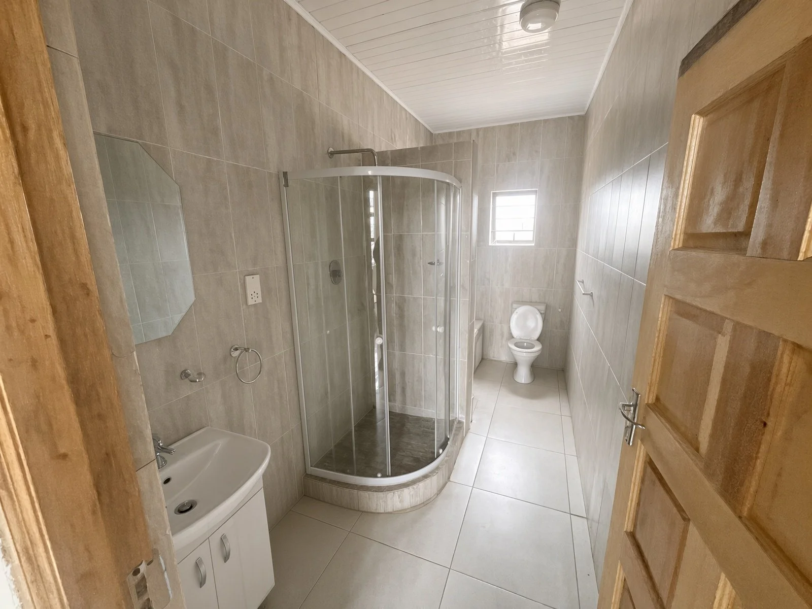 Ensuite bathroom with glass shower, basin cabinet and toilet, house for sale in Gaborone North
