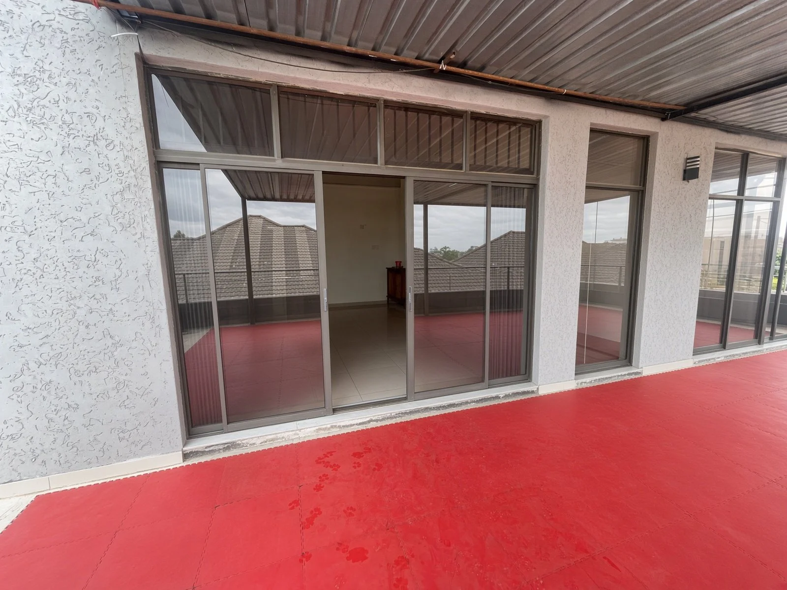 Large sliding glass doors opening onto a rooftop terrace with red mats at a house for sale in Gaborone