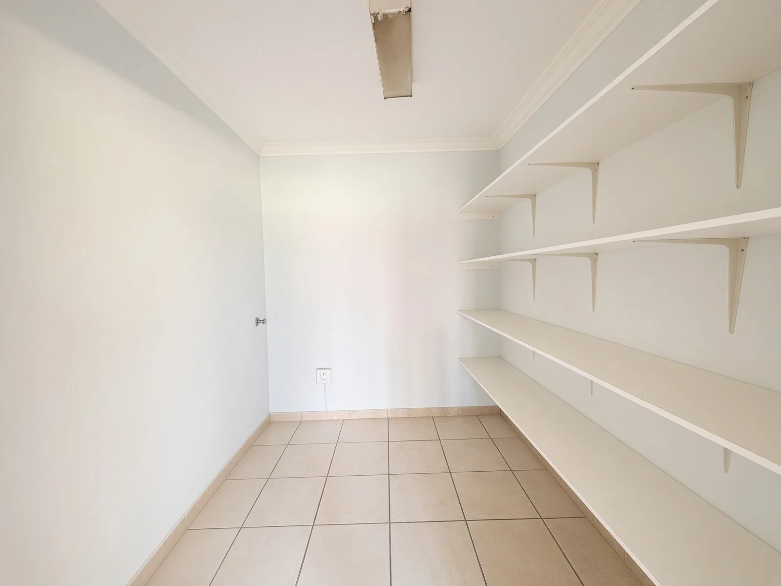 Pantry with white wall shelves in a 5-bedroom house for sale in Phakalane Golf Estate