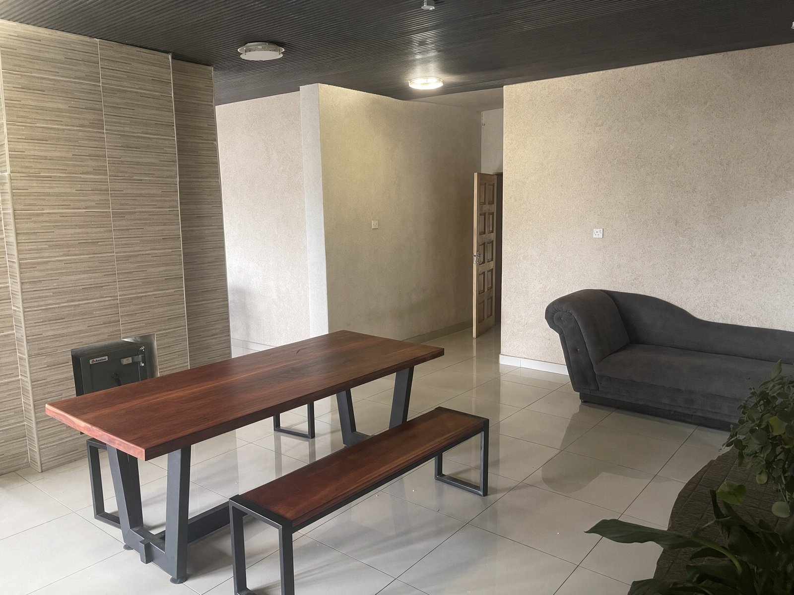 Dining room with solid wood table, bench seating and grey chaise, family house for sale in Gaborone