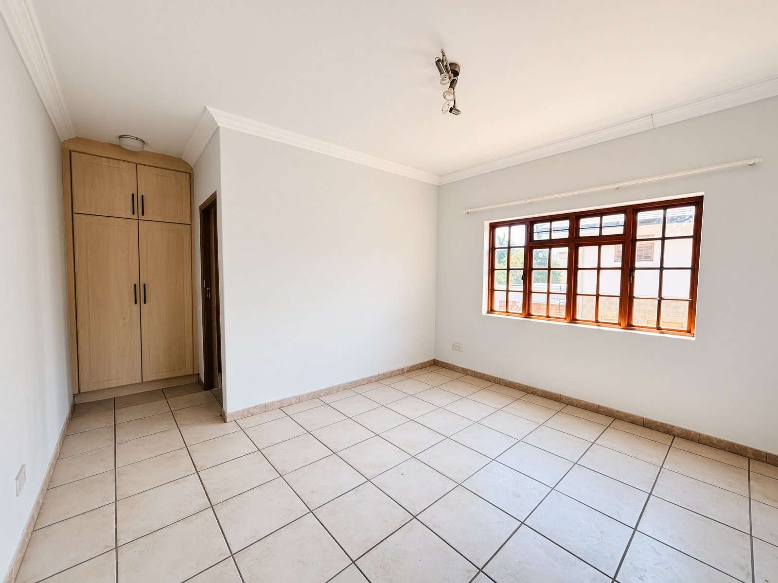 Bedroom with light wood built-in wardrobe and window in a Phakalane house for sale