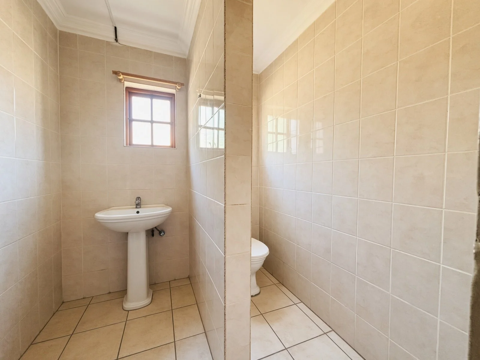 Guest toilet with pedestal basin and tiled walls in a 5-bedroom house for sale in Phakalane Golf Estate