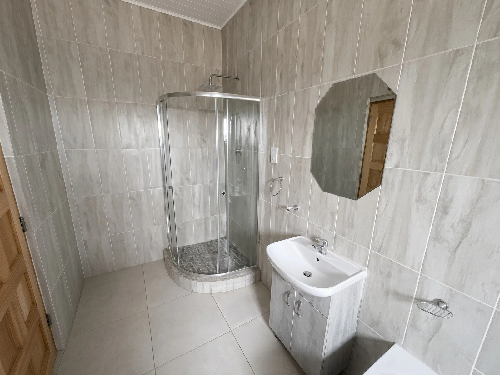 Tiled shower bathroom with glass cubicle, vanity and octagonal mirror, family home Gaborone