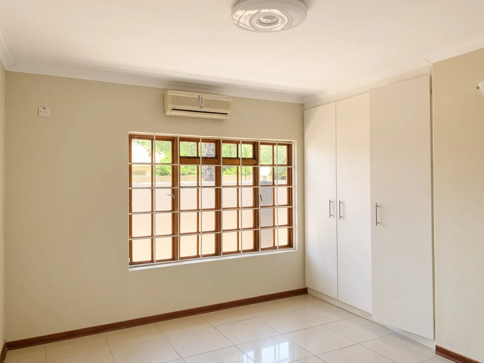 Bedroom with fitted wardrobe, air conditioning and barred window in a 4-bedroom house for rent in Phakalane