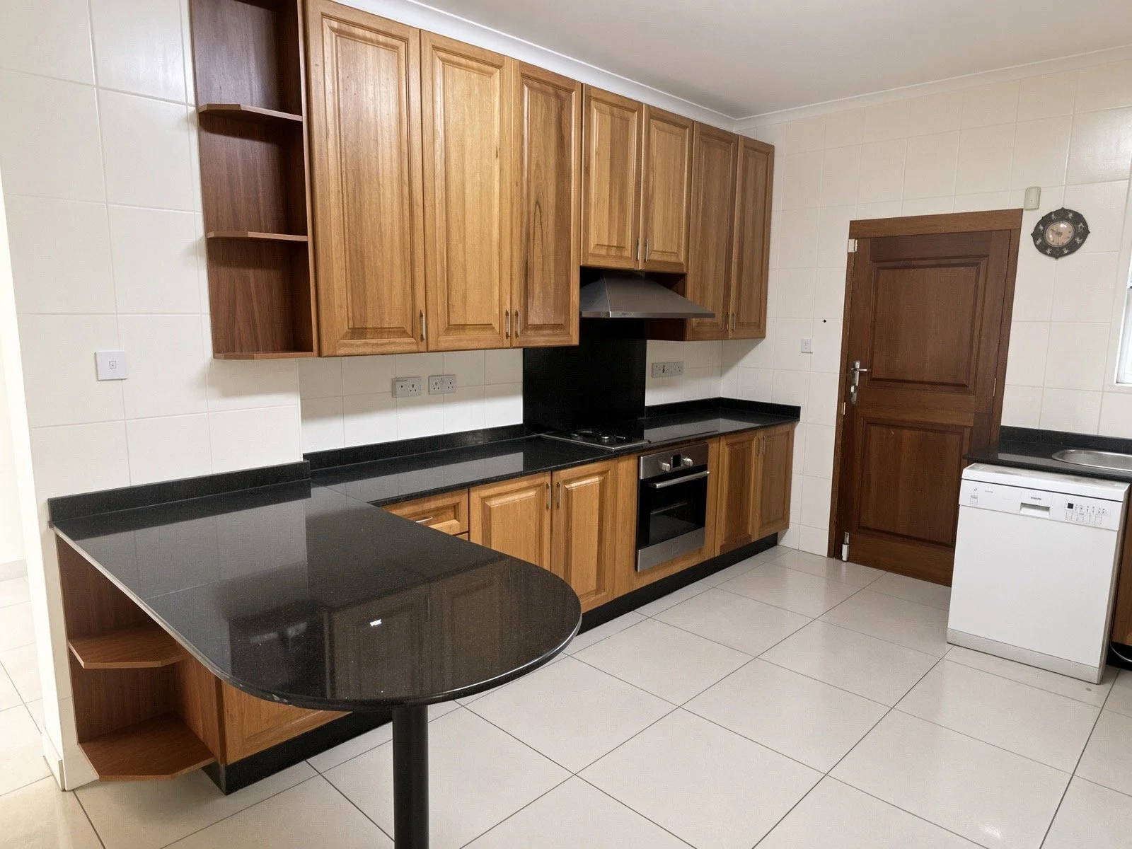 Fully fitted kitchen with wooden cabinets, black granite, oven, dishwasher and breakfast bar in the 4-bedroom Phakalane rental. Nestgeeks.