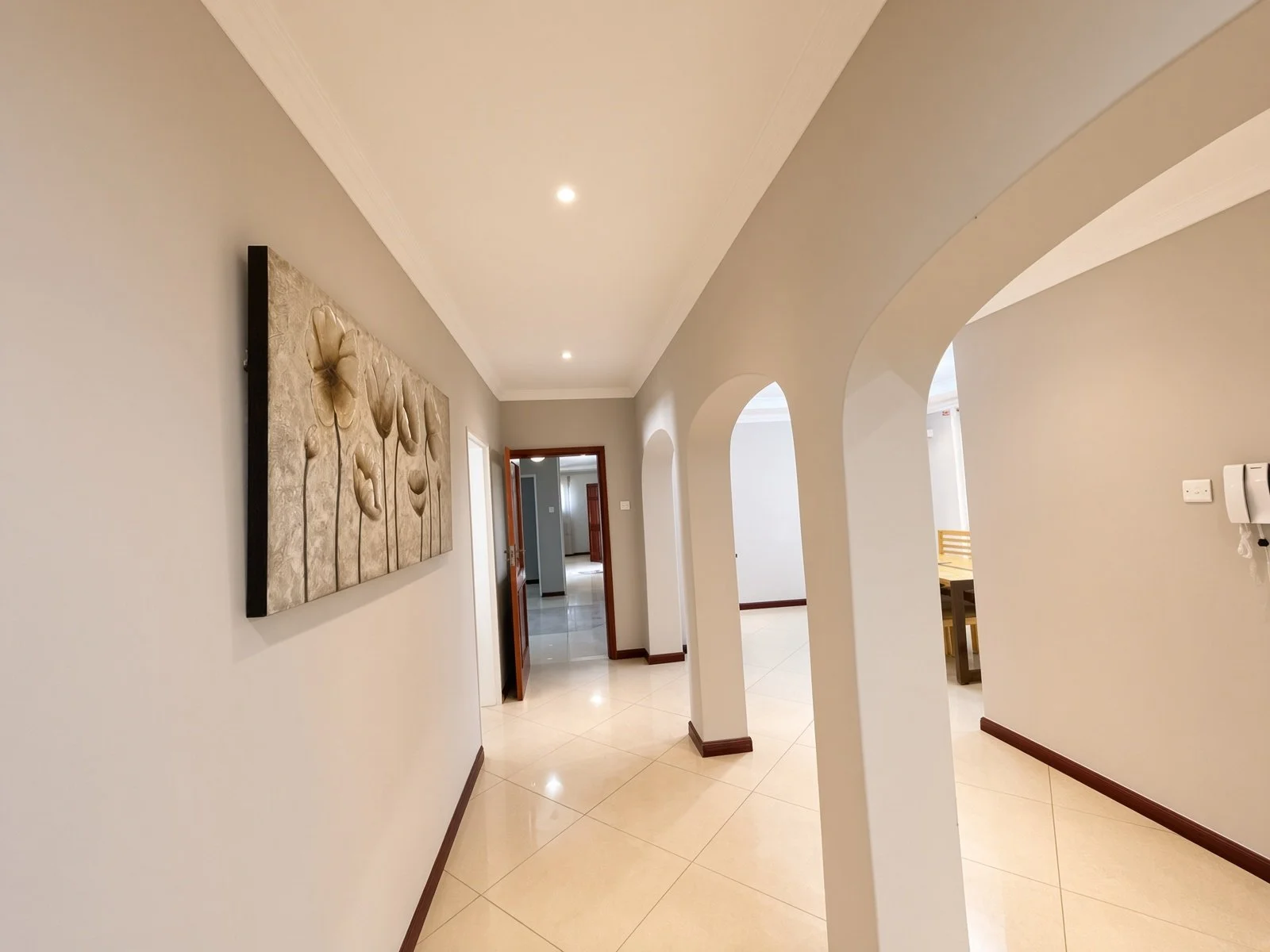 Interior hallway with floral wall art and arches in the fully furnished 5-bedroom house for rent in Phakalane. Nestgeeks listing.