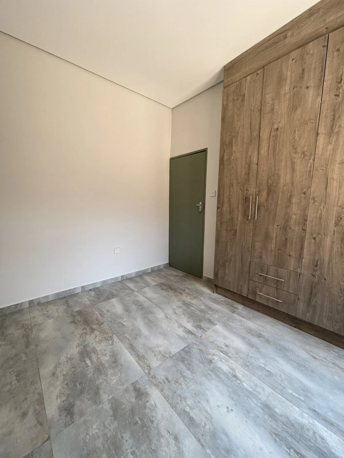 Bedroom with wood-finish built-in wardrobe and grey tiles in a Maruapula house for rent