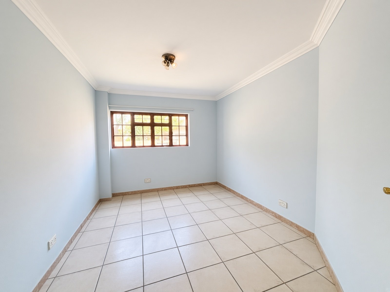 Empty bedroom with window and ceiling light in a 5-bedroom house for sale in Phakalane Golf Estate