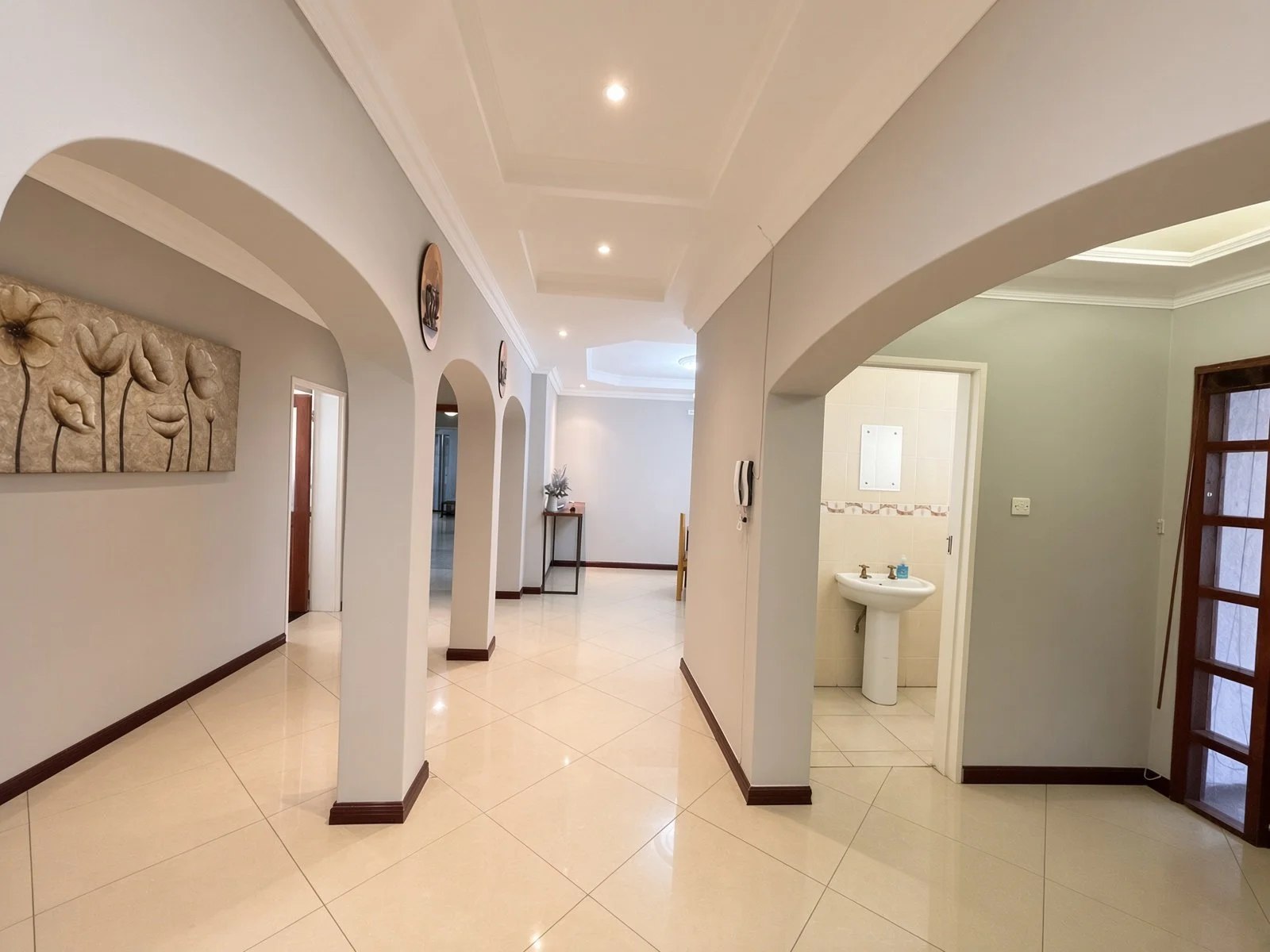 Arched hallway with guest toilet and basin visible in the fully furnished 5-bedroom house for rent in Phakalane. Nestgeeks.