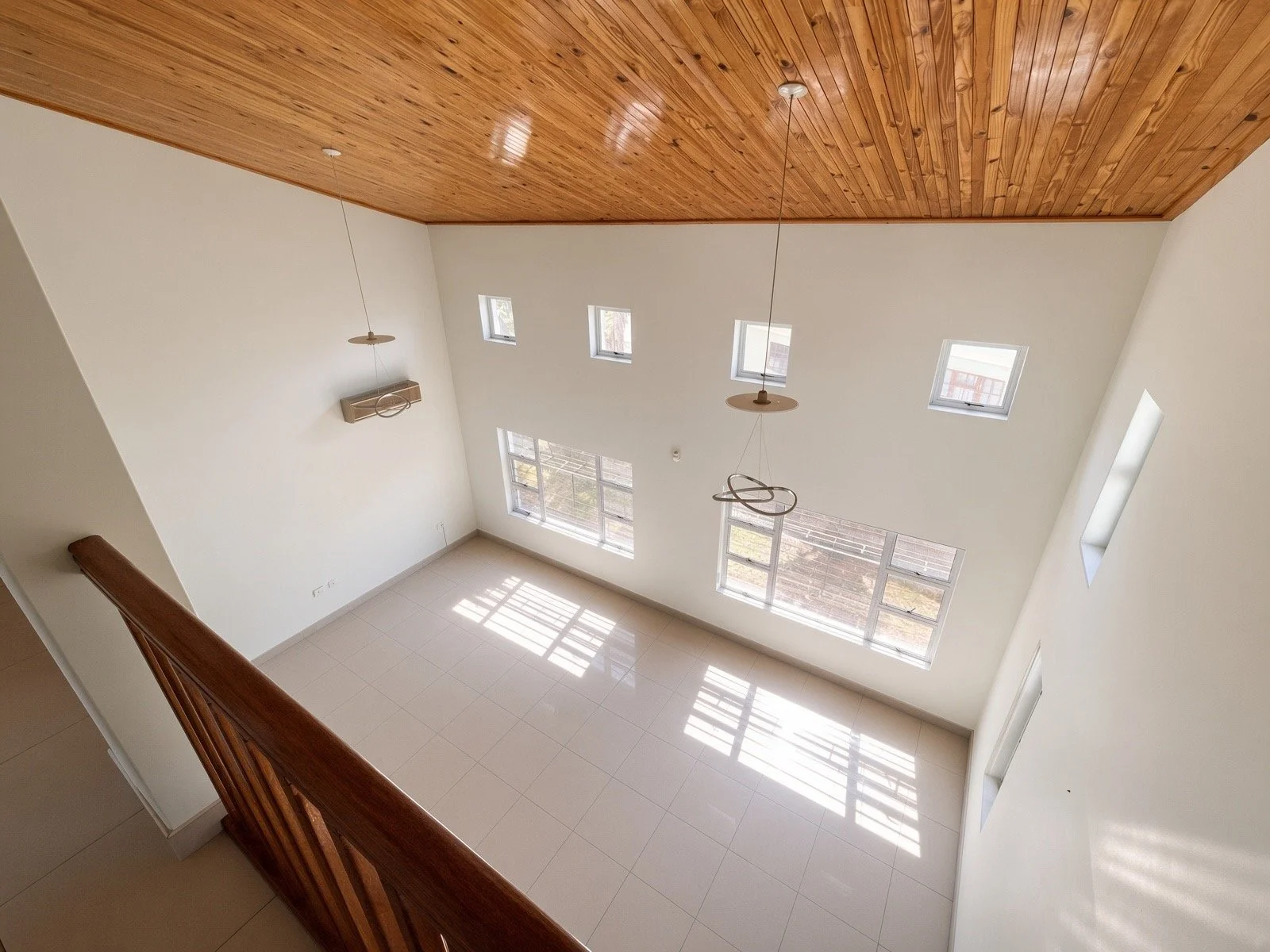 Double-volume living area with wooden ceiling, high windows and tiled floors in the 4-bedroom house for rent in a gated estate, Phakalane. Nestgeeks.