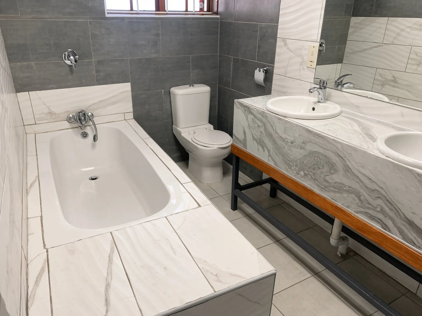 Common bathroom with bathtub and marble double vanity in a Phakalane house for rent