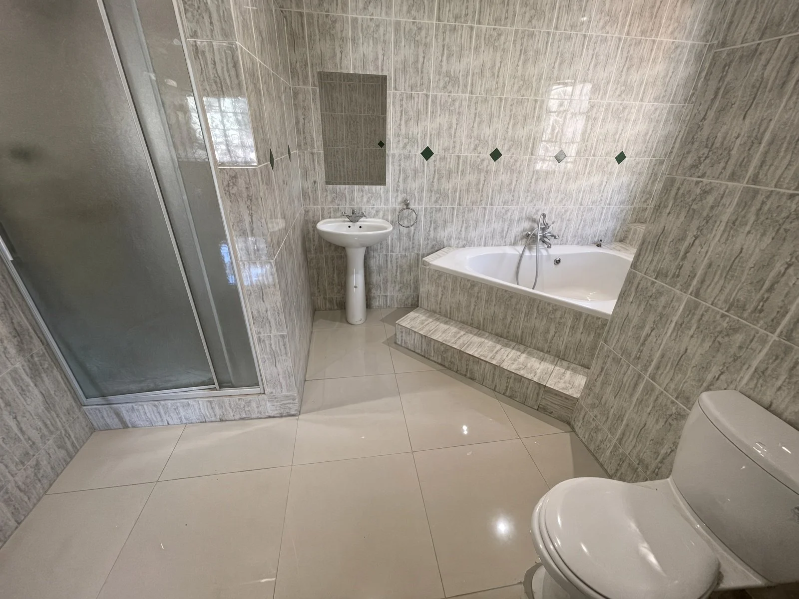Common bathroom with glass shower, bathtub and pedestal basin in a 5-bedroom house for rent in Block 9