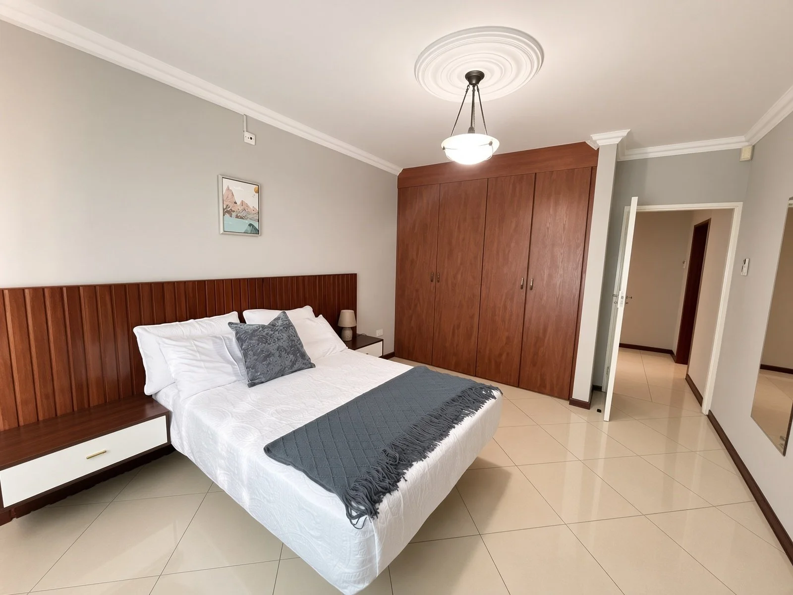Master-style bedroom with extensive wooden fitted wardrobes and ensuite access in the fully furnished 5-bedroom house for rent in Phakalane. Nestgeeks.