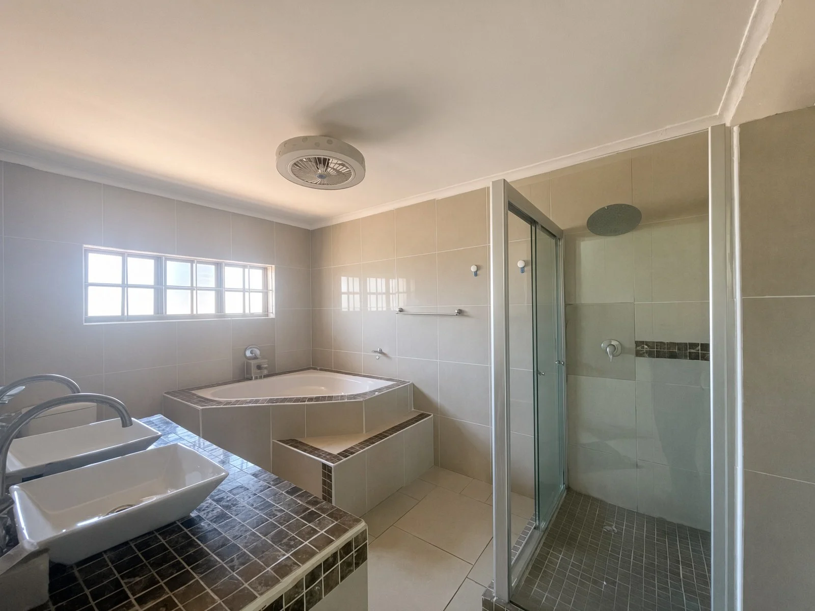 Master ensuite with corner bathtub, glass shower and double vessel basins in a Phakalane house for rent