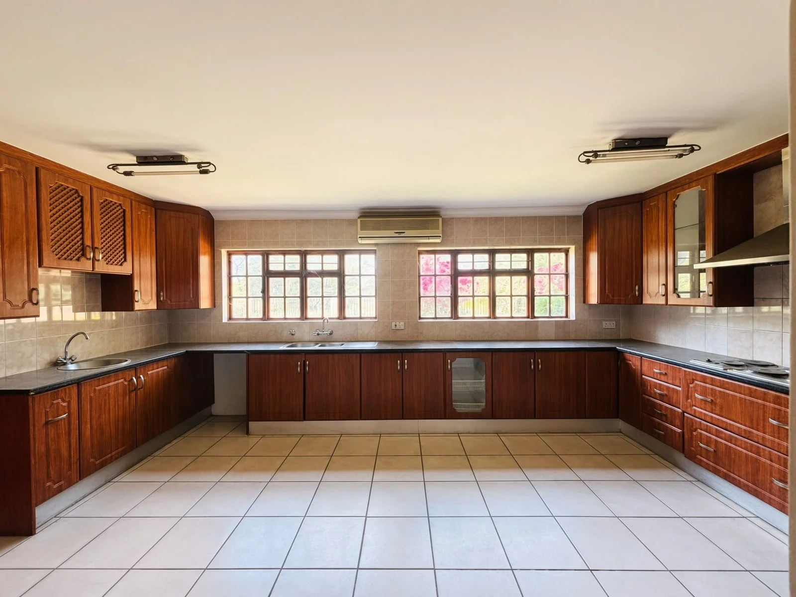 Spacious kitchen with dark wood cabinets, black counters and windows in a Phakalane house for sale