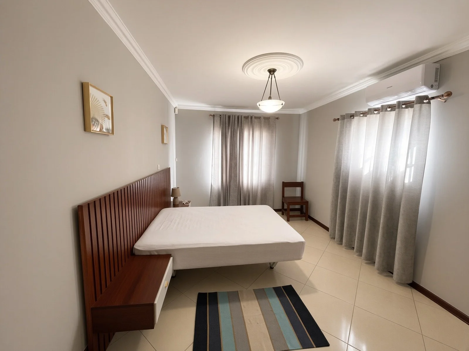 Air-conditioned bedroom with slat headboard and grey curtains in the fully furnished 5-bedroom house for rent, Phakalane. Nestgeeks.