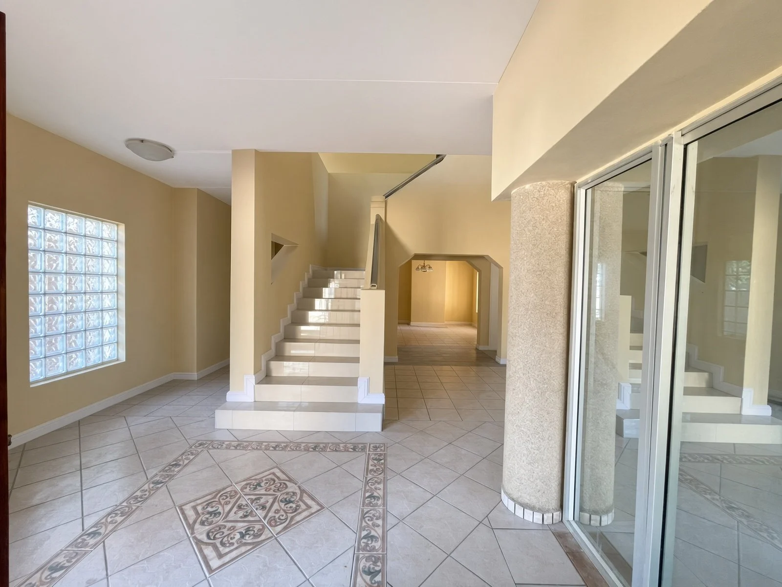 Entrance hall with tiled staircase, glass-block window and feature floor tiles in a Block 9 Gaborone house for rent